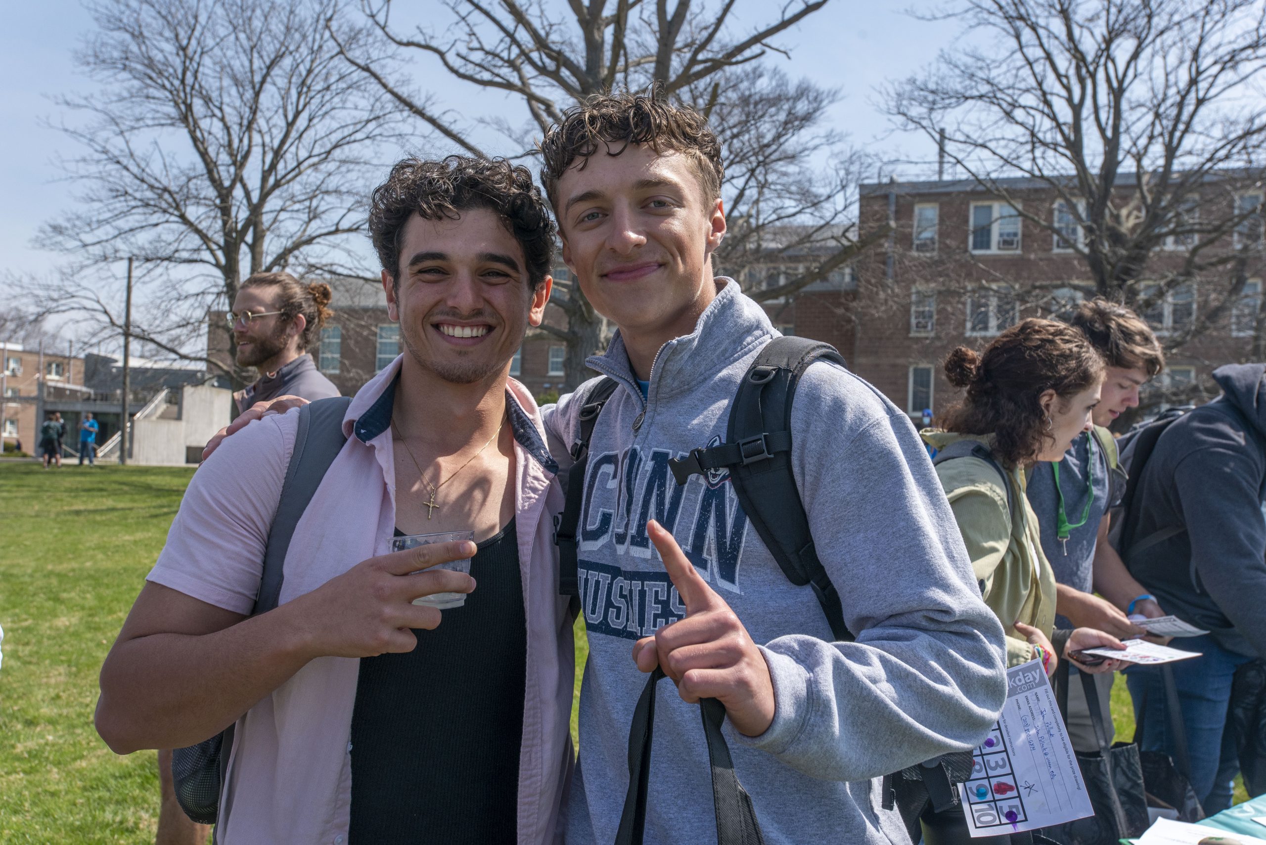 Students outdoors during an event at the UConn Avery Point campus. Student holding up one finger to represent one week before classes start. April 14, 2022. (Sean Flynn)