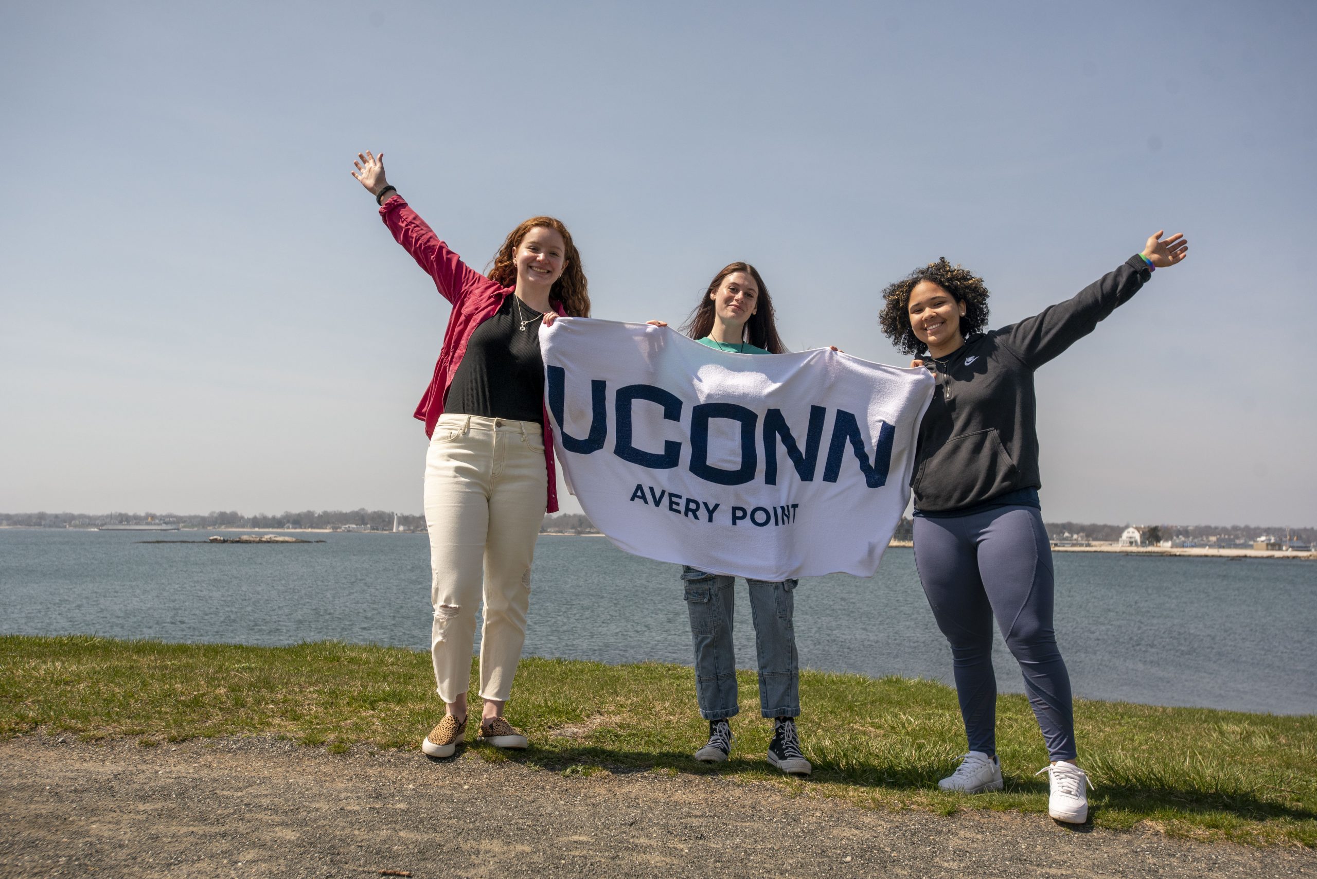 Students holding a Uconn Avery Point banner at the UConn Avery Point campus. April 14, 2022. (Sean Flynn)